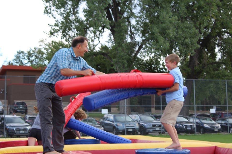 Person and child on an inflatable jousting game