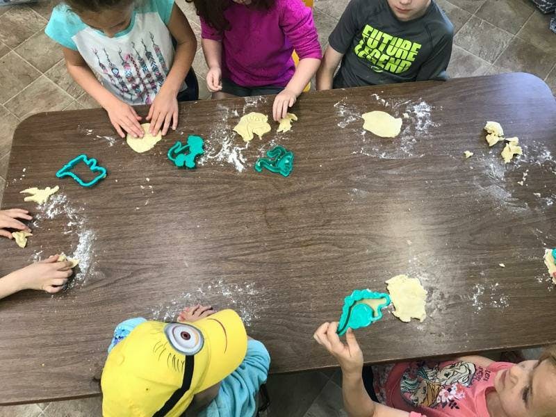 Children making shapes with dough and cookie cutters on a table