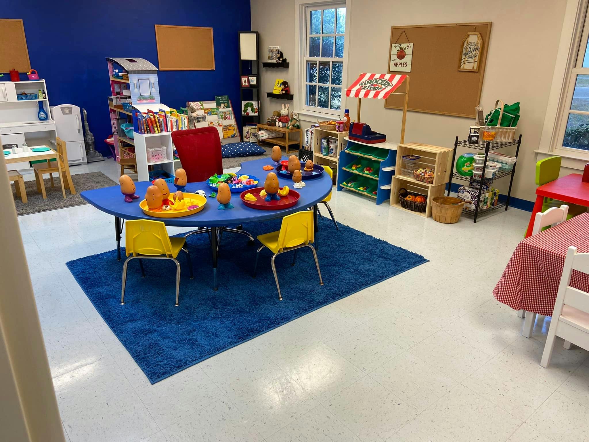 Playroom with blue walls, blue rug, and small tables with chairs