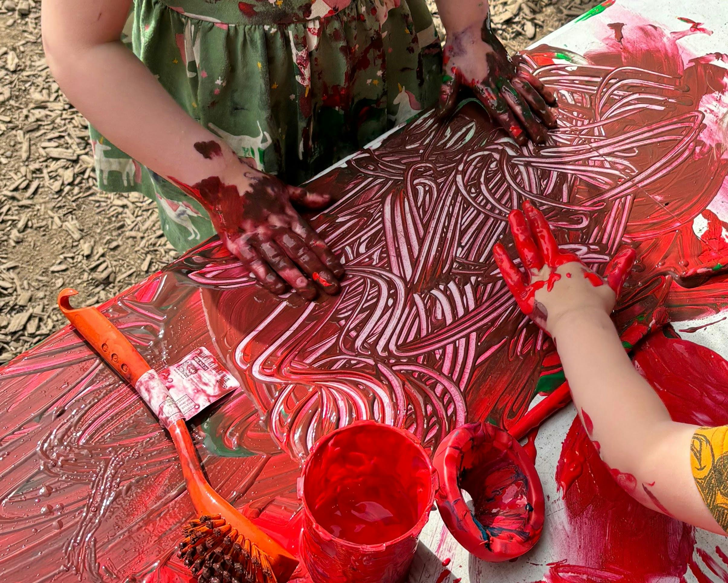 People with paint-covered hands making finger art on a table