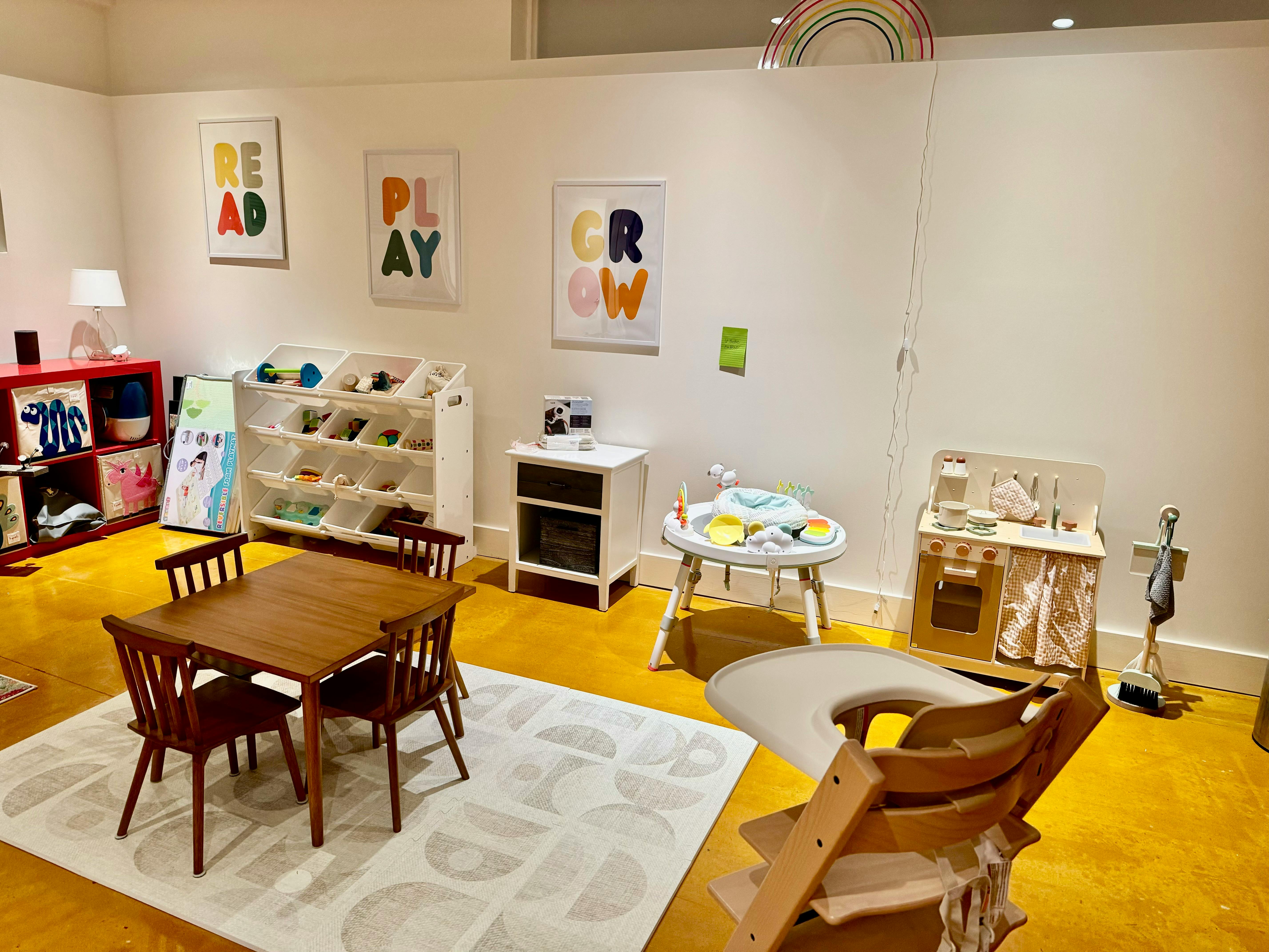 Children's play area with small table and chairs, toys, and wall art