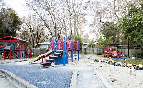 Playground with red and blue play structure and sandbox