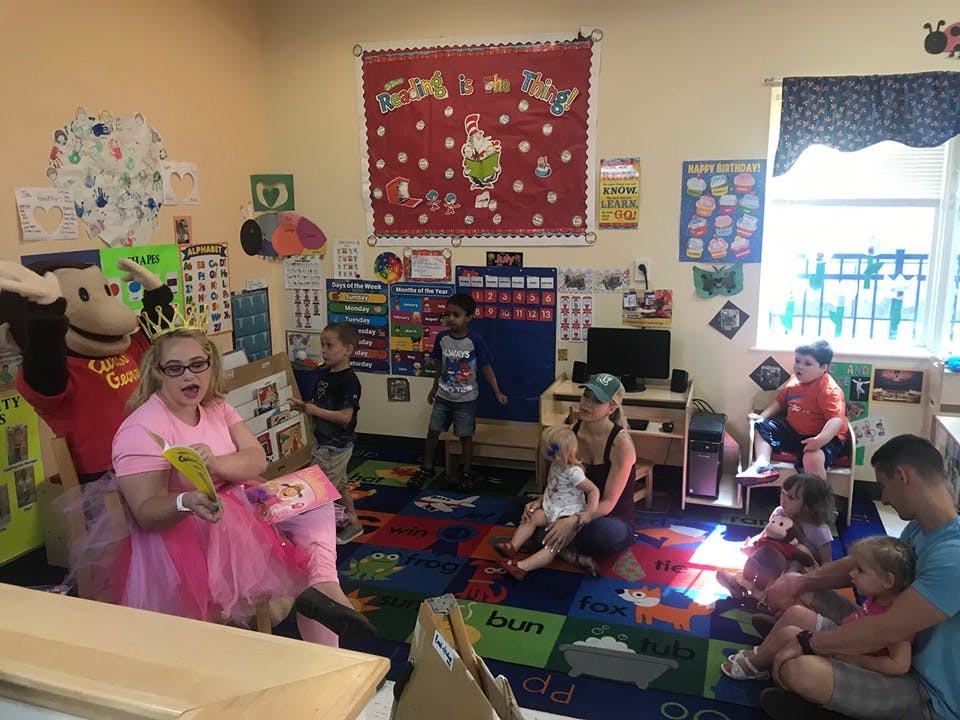 Person in pink dress reading to children in a classroom