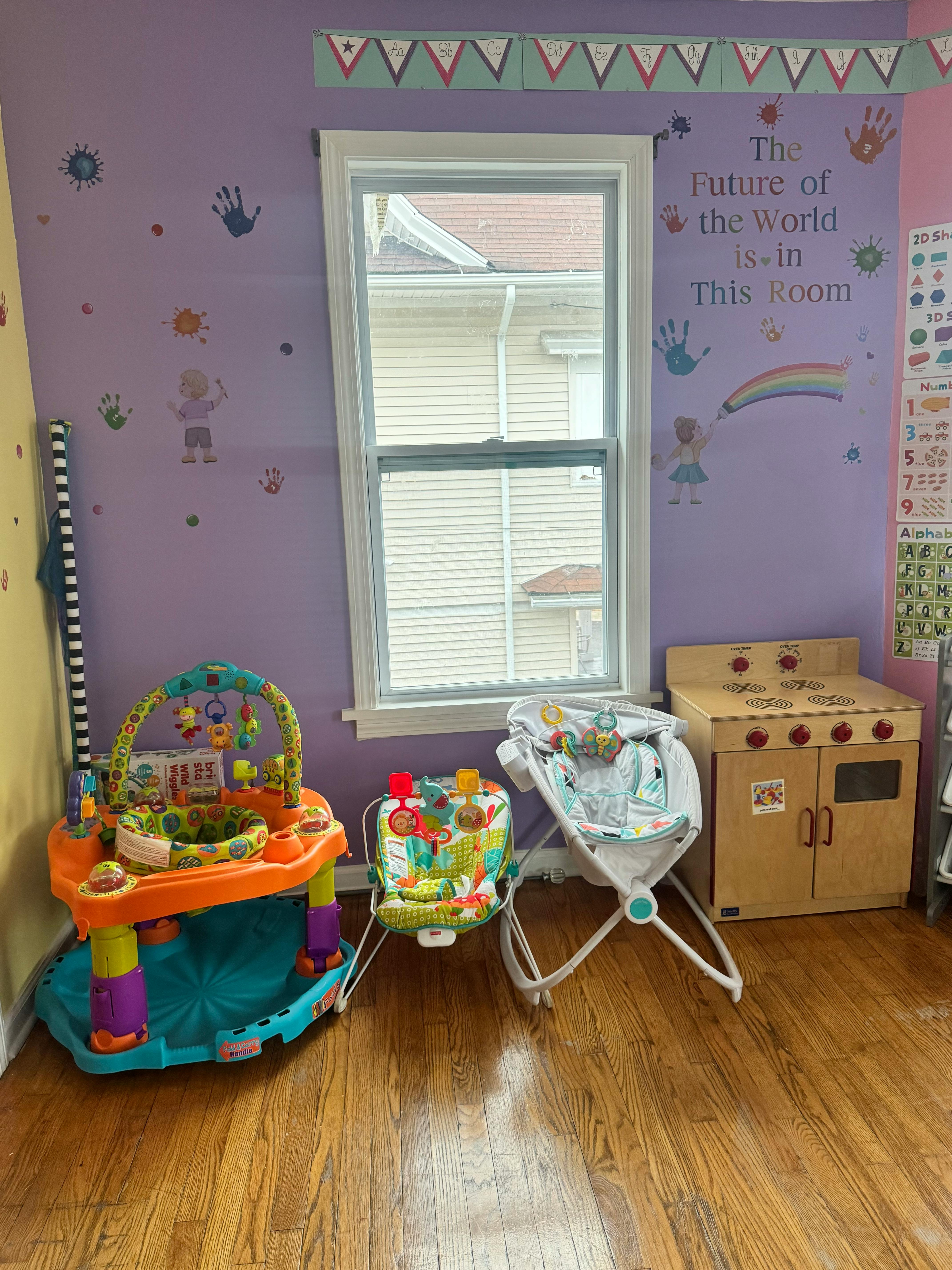 Baby activity center, bouncer, and toy kitchen in a room with purple walls