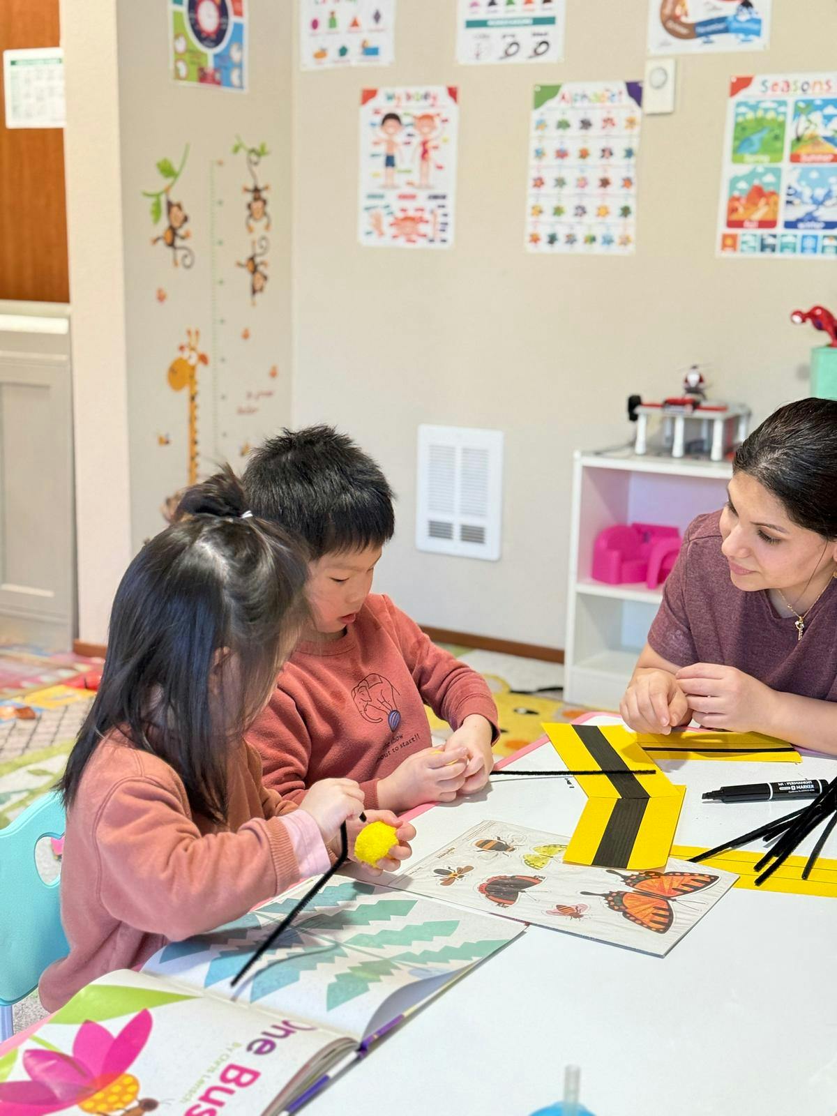 Adult and two children at a table with craft supplies