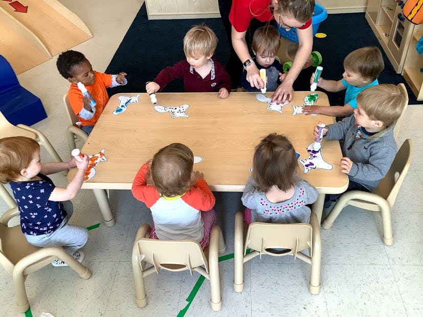 Adult and children sitting at a table doing an art activity