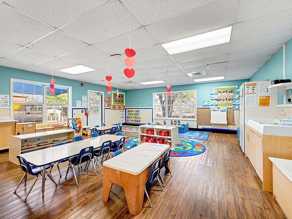 Classroom with small tables and chairs, play mats, and heart decorations