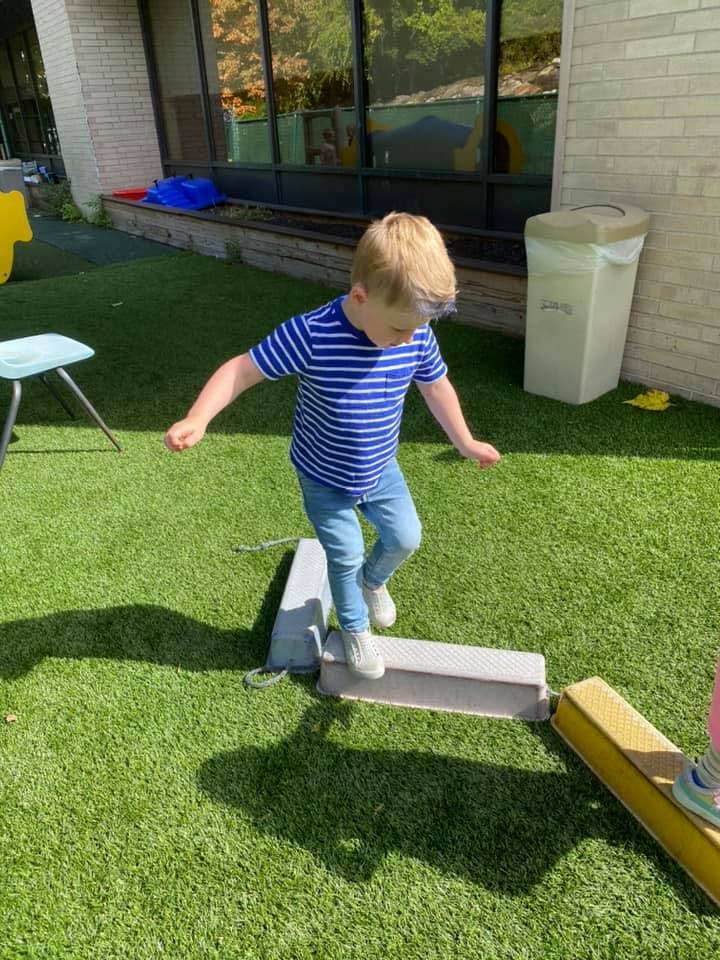 Child walking on balance beams on artificial grass
