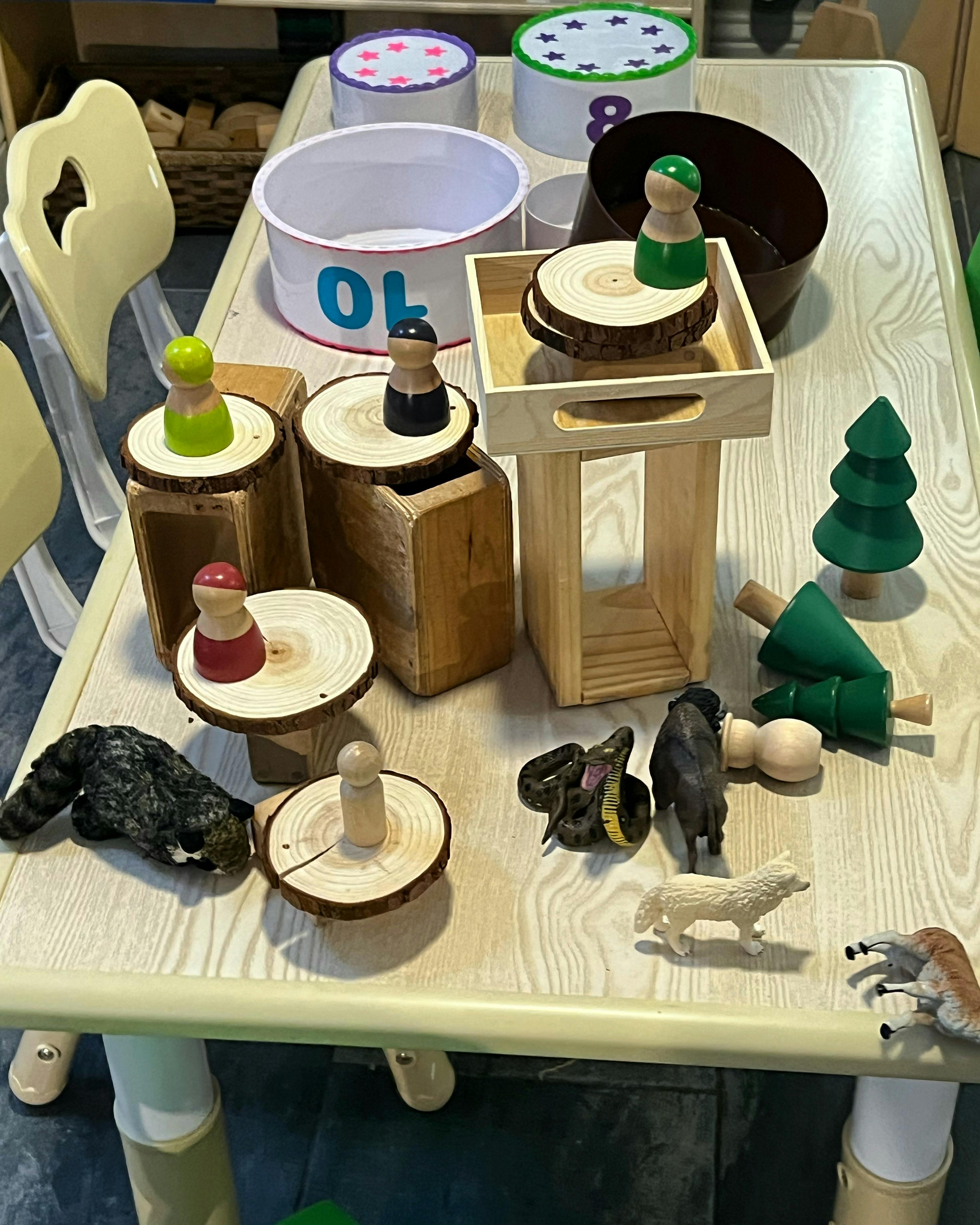 Table with wooden toys, animal figurines, and number containers