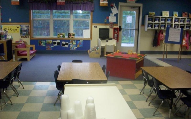 Empty classroom with tables and chairs, toys, and bulletin board displays