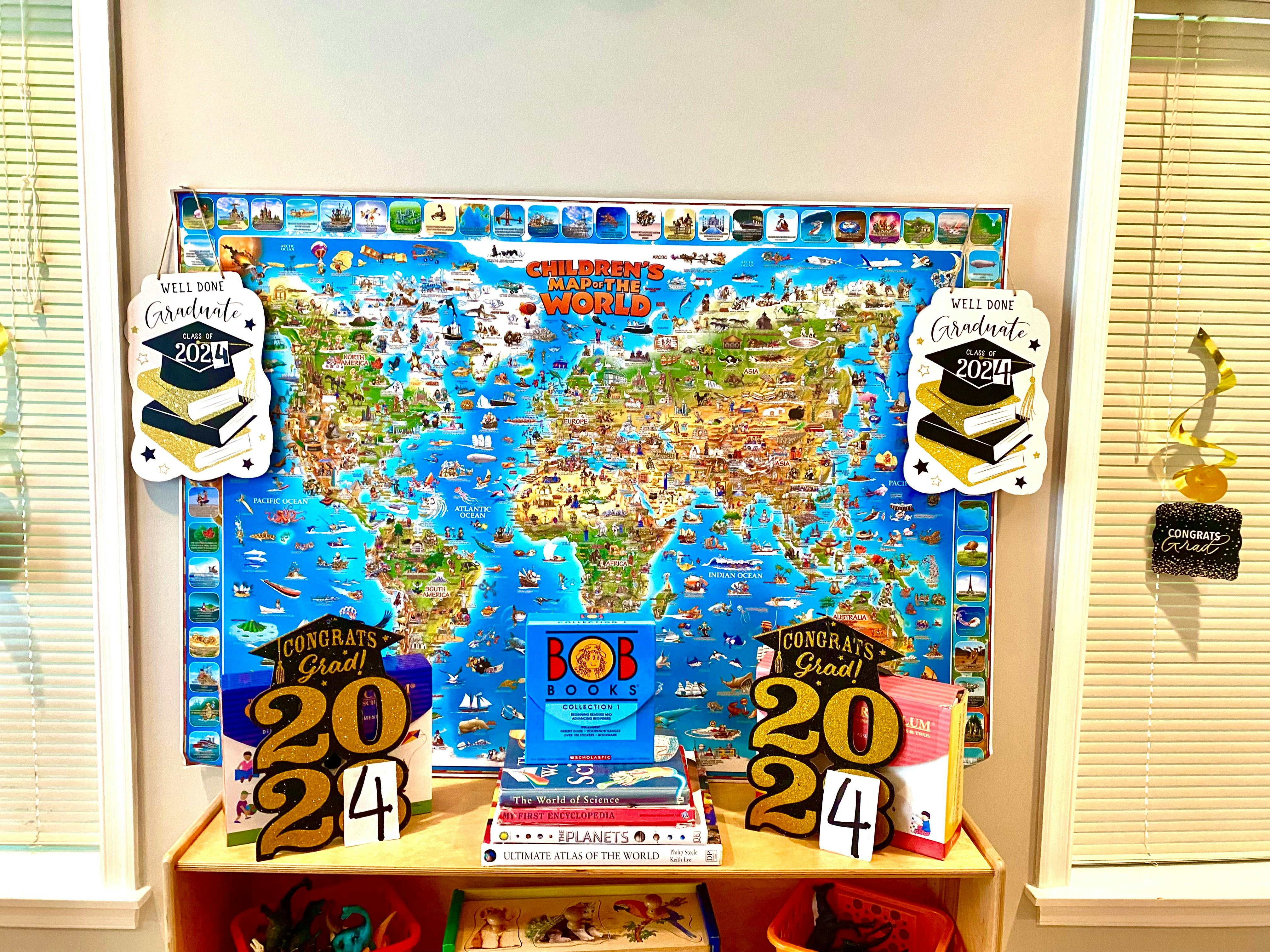 World map with graduation decorations and books on a shelf with books