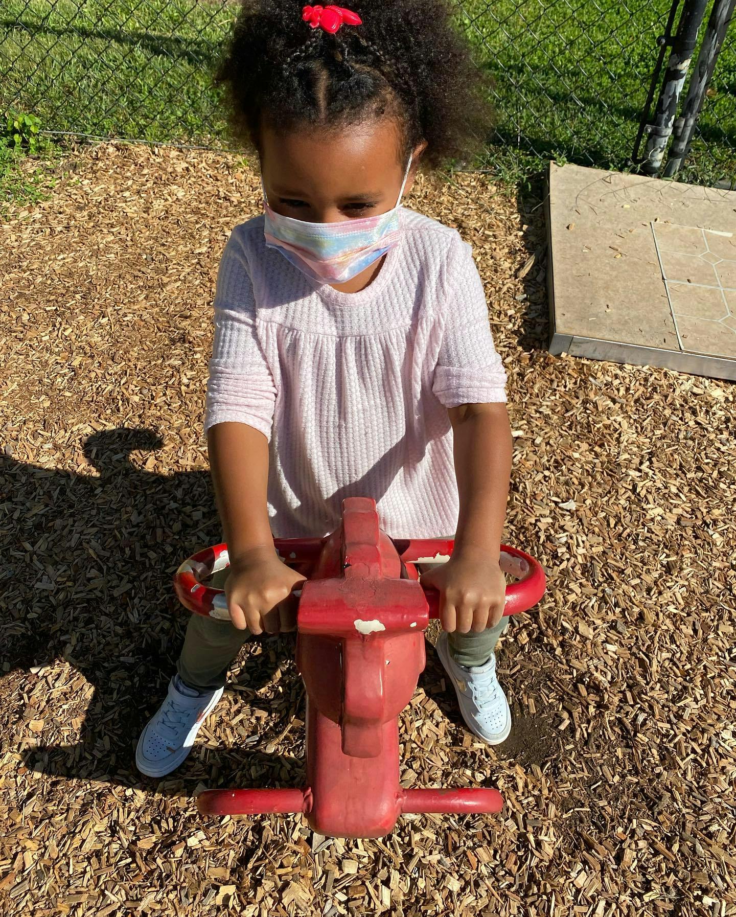 Child wearing a mask on a red spring rider