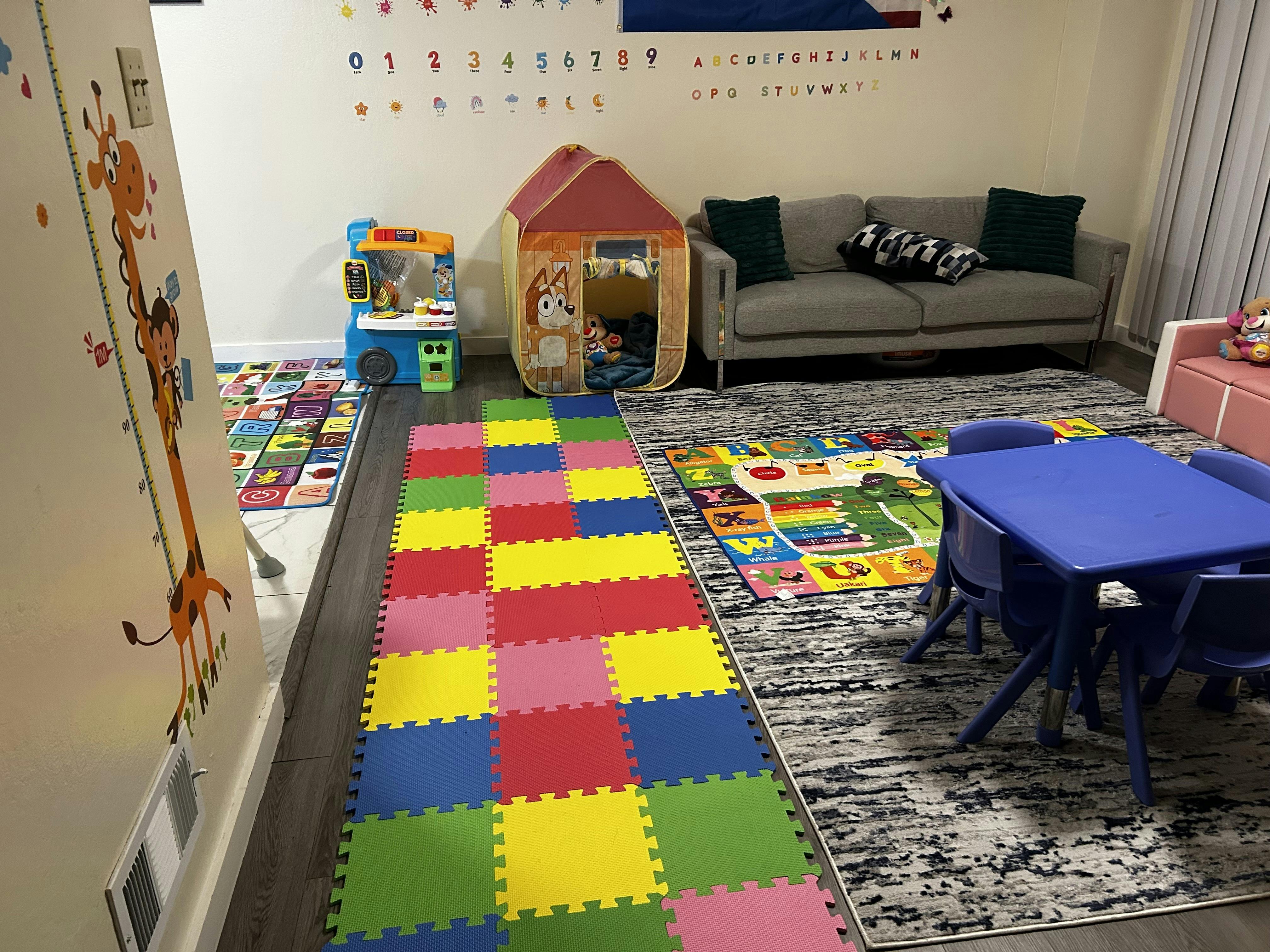 Playroom with colorful floor mats, a small tent, and a blue table with chairs