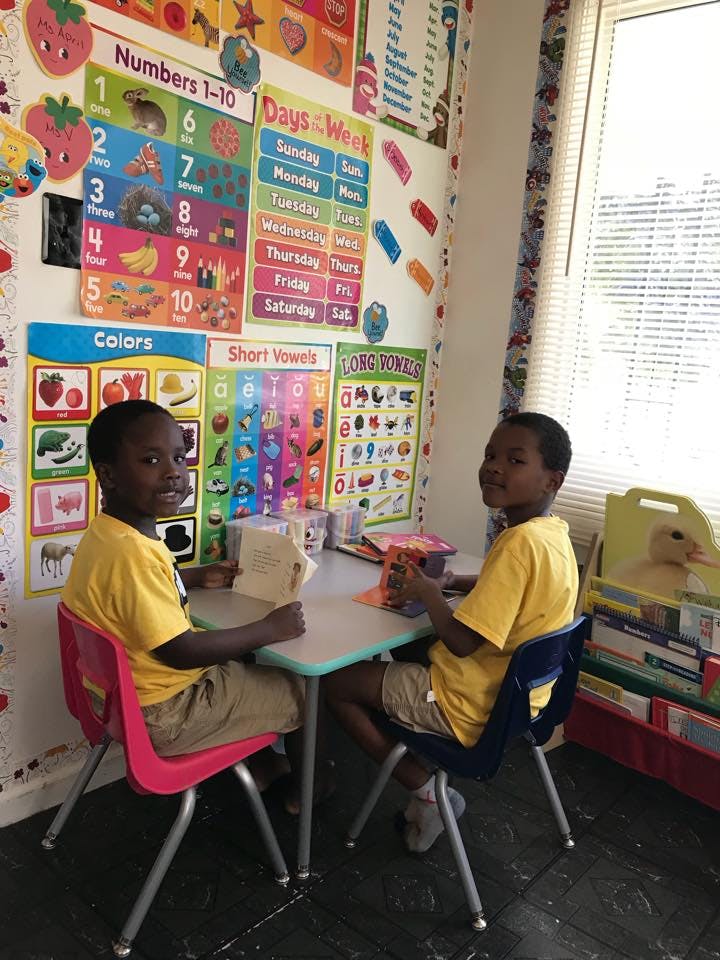Two children sitting at a table in a classroom