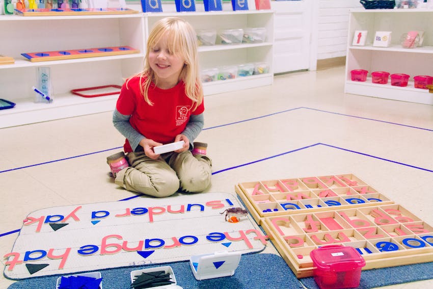 Child kneeling on floor with learning materials