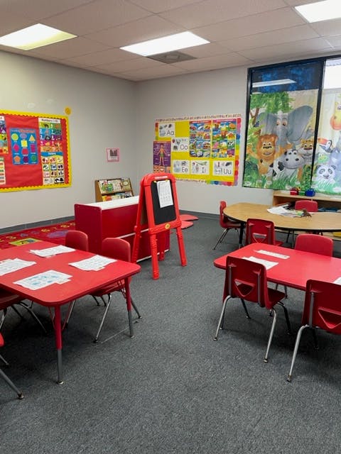Classroom with red tables and chairs, bulletin boards, and an easel