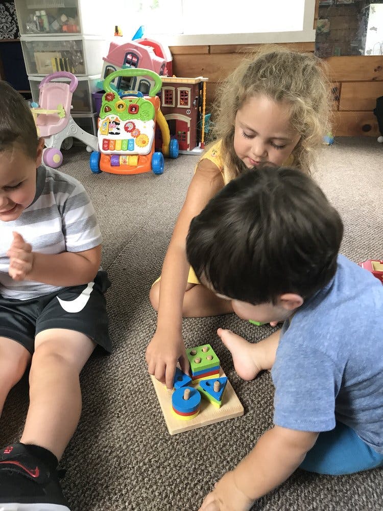 Three children playing with a shape sorter puzzle on the floor
