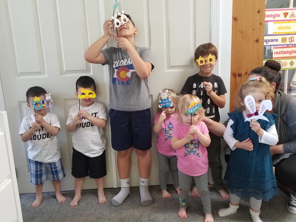 Group of children holding up masks to their faces