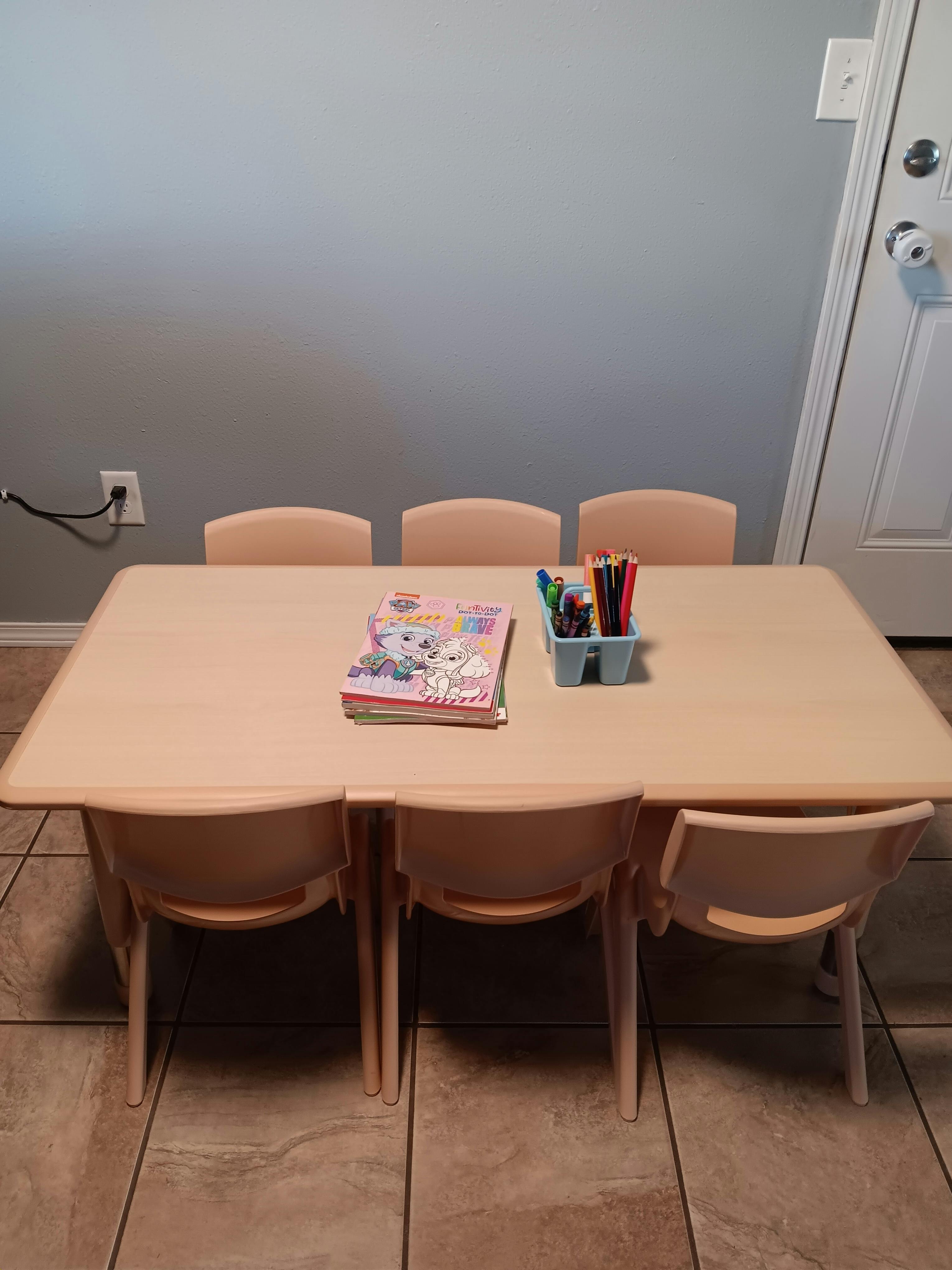 Children's table with chairs, books, and markers