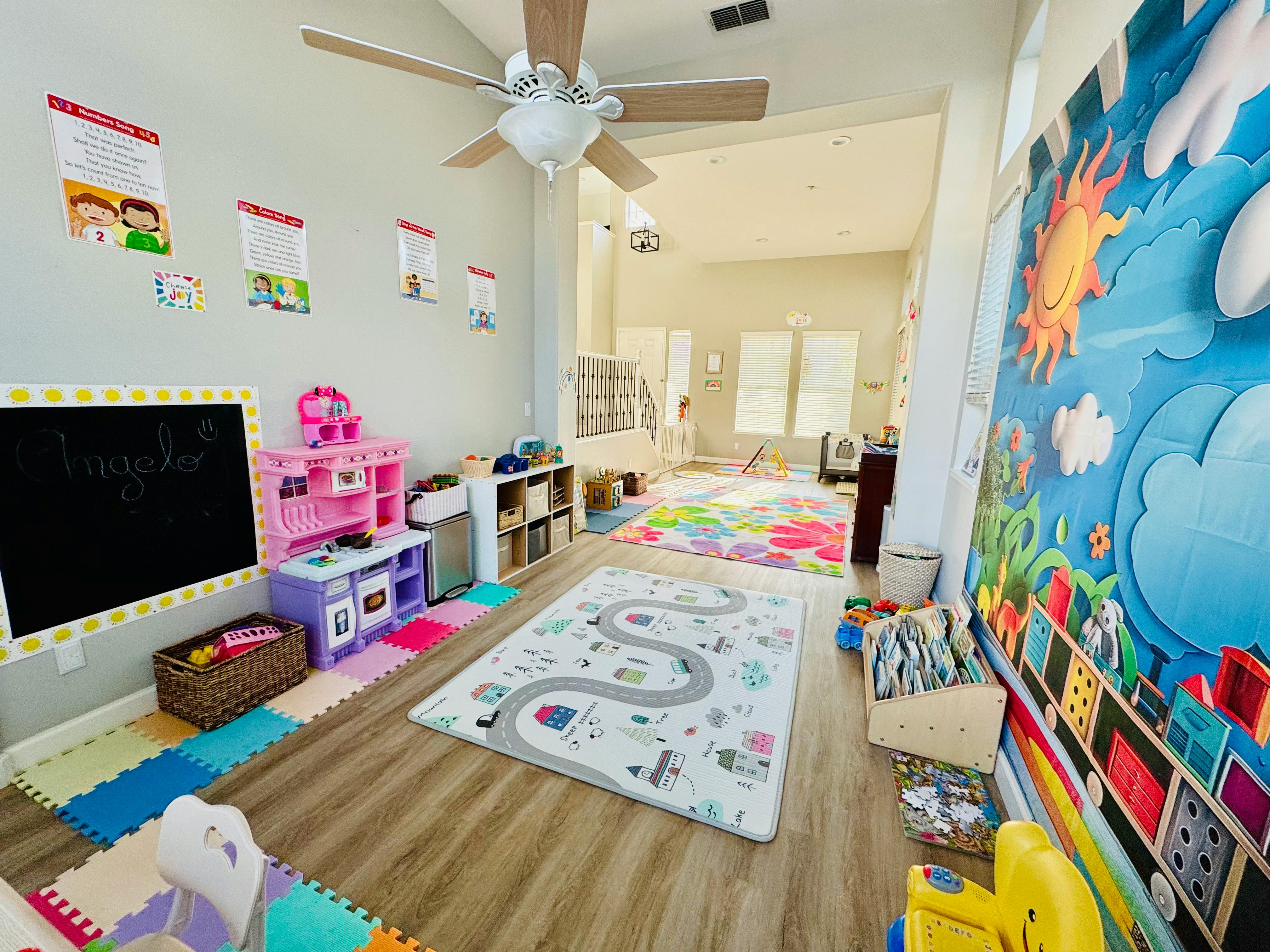 Playroom with colorful rugs, a chalkboard, and toy shelves