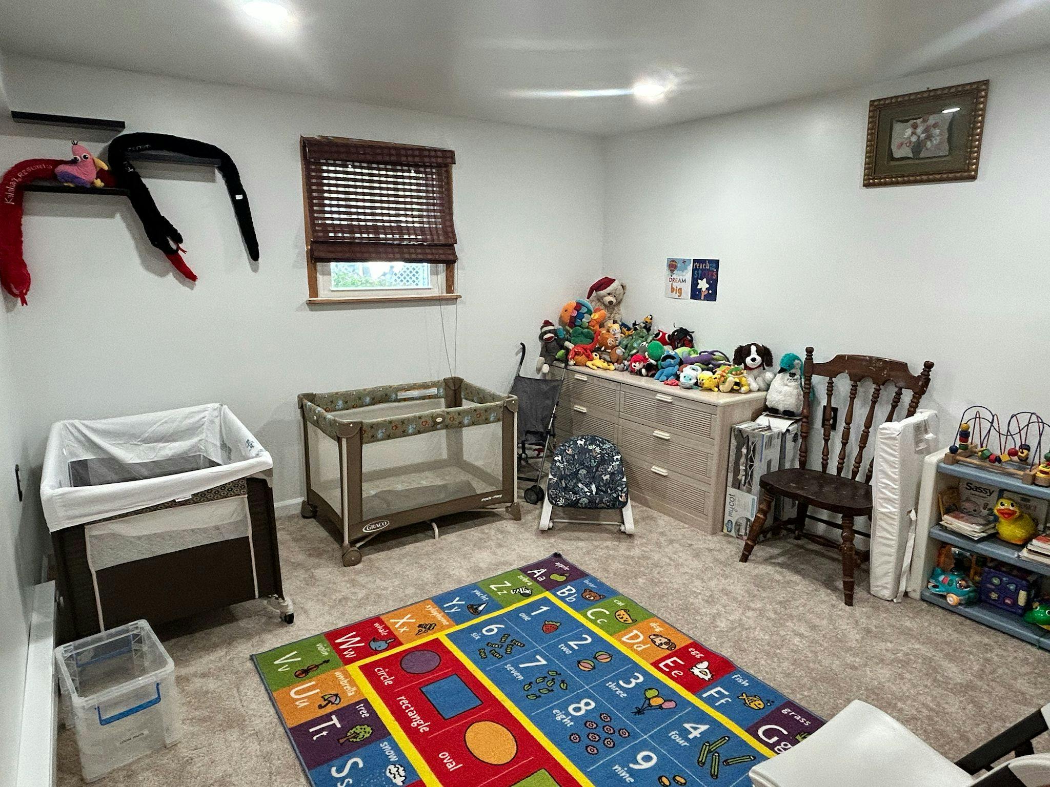Playroom with two playpens, a wooden chair, and an educational alphabet rug
