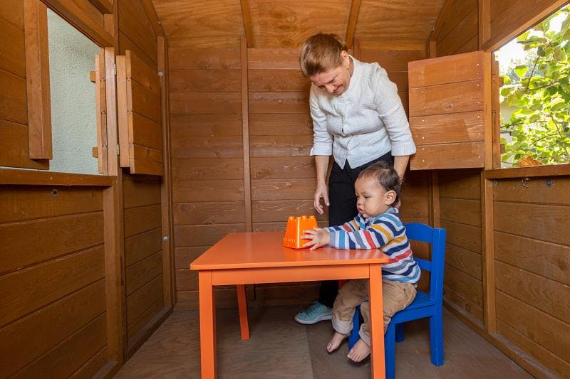 Adult and child playing with toy at small table