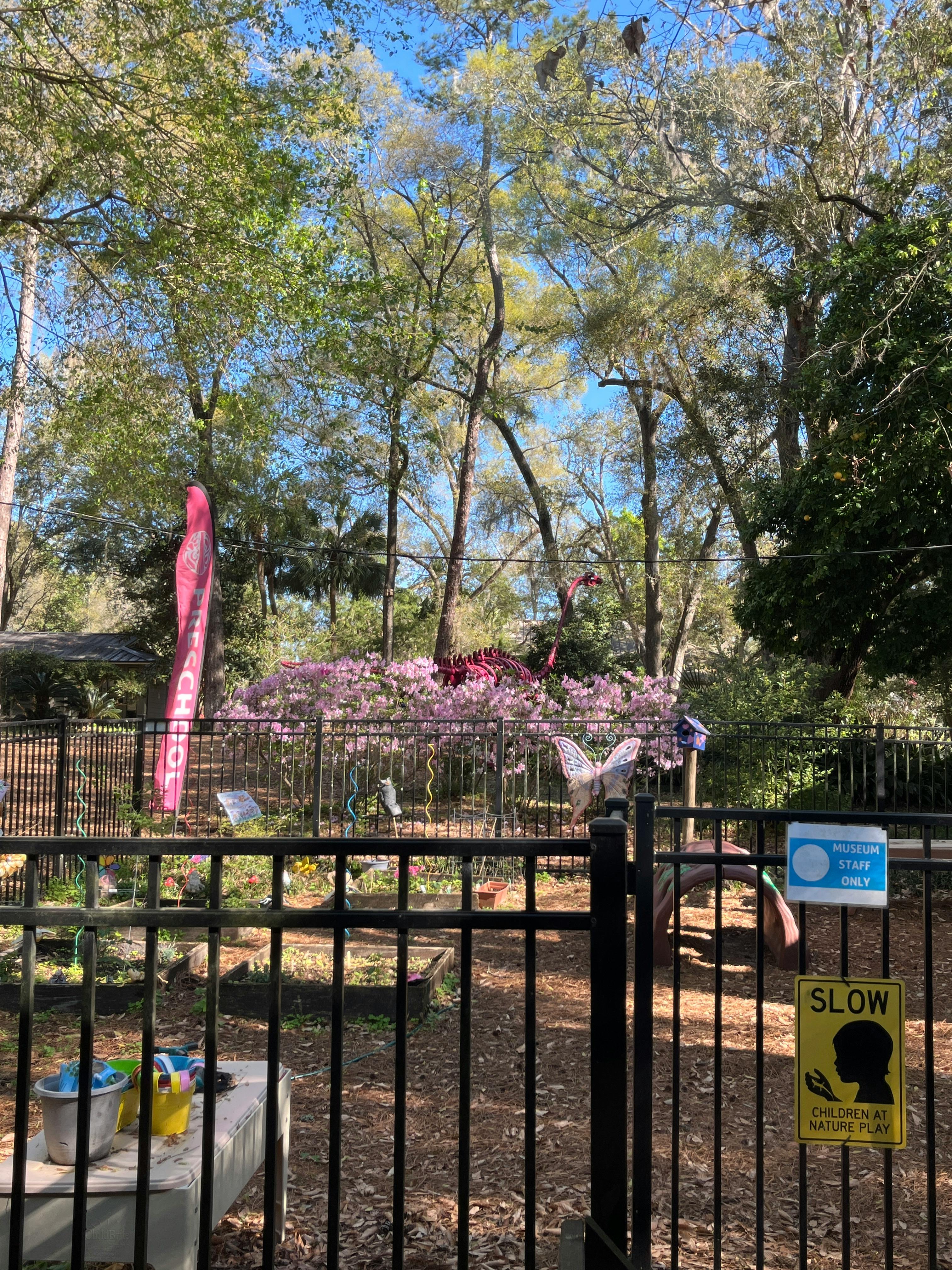 Fenced garden with pink flowers and trees in the background