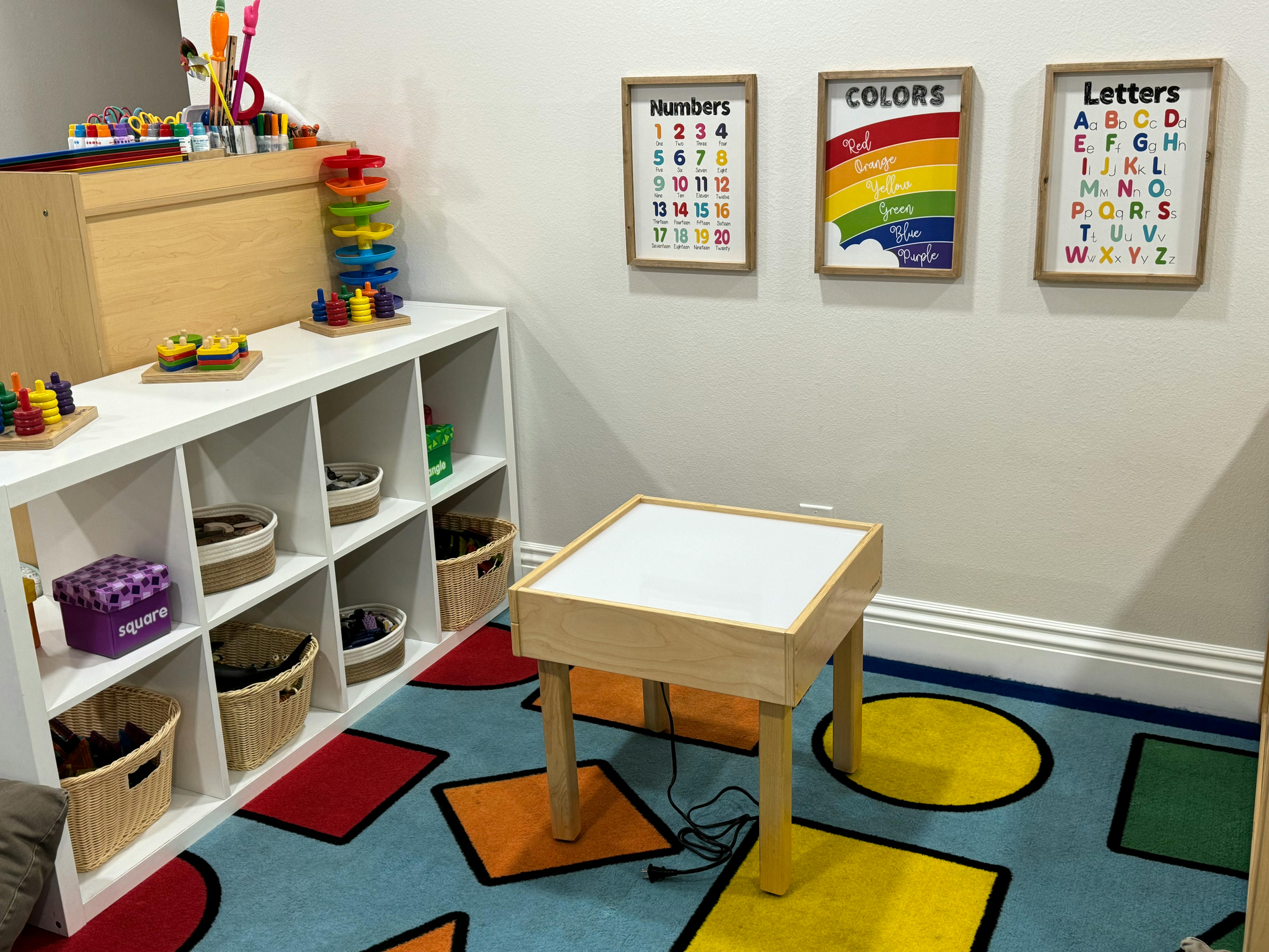Classroom with shelves of toys, a light table, and educational posters