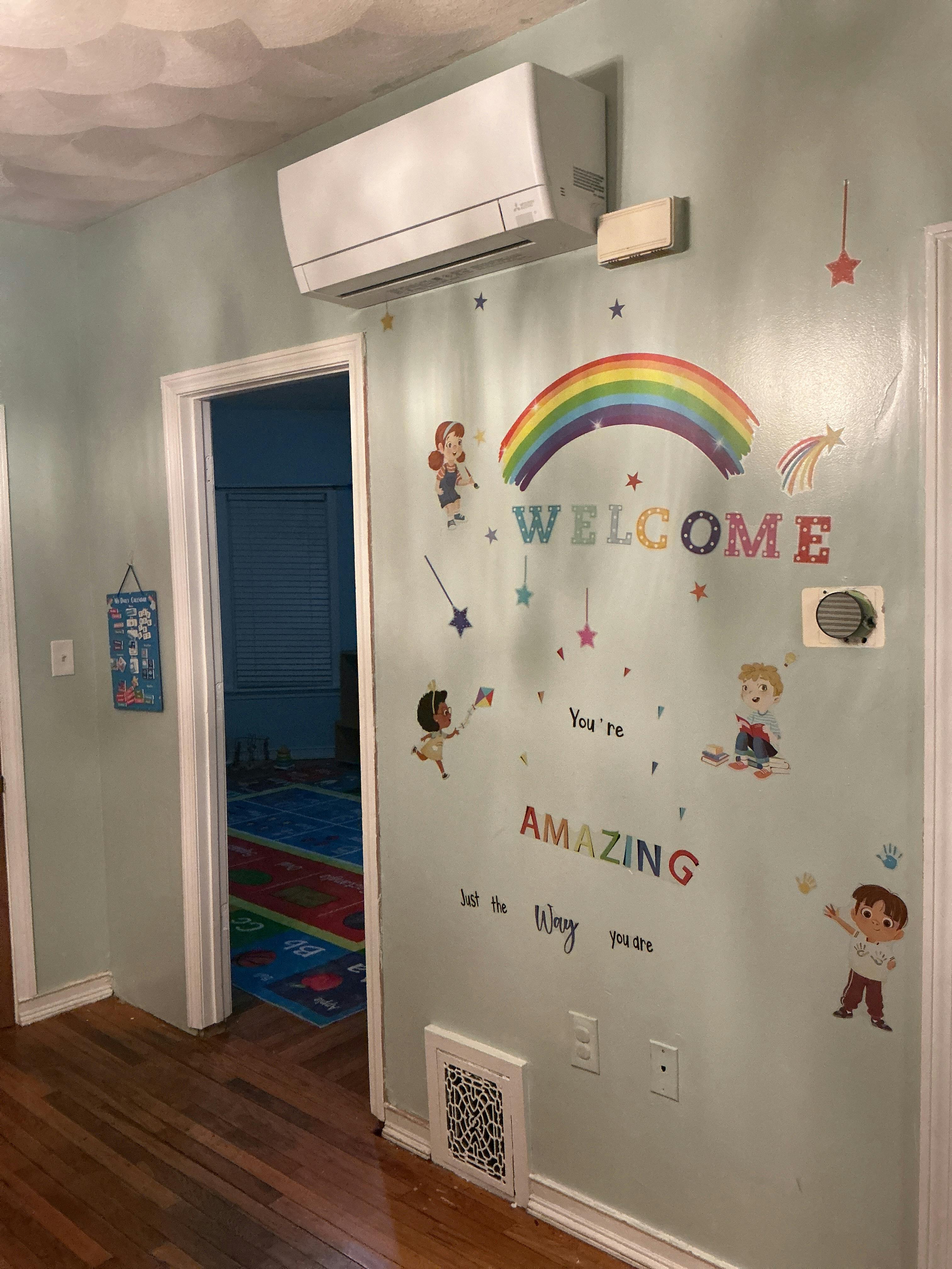 Wall with children's decals, including a rainbow and the word "WELCOME"