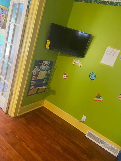 Television mounted on a green wall with educational decorations