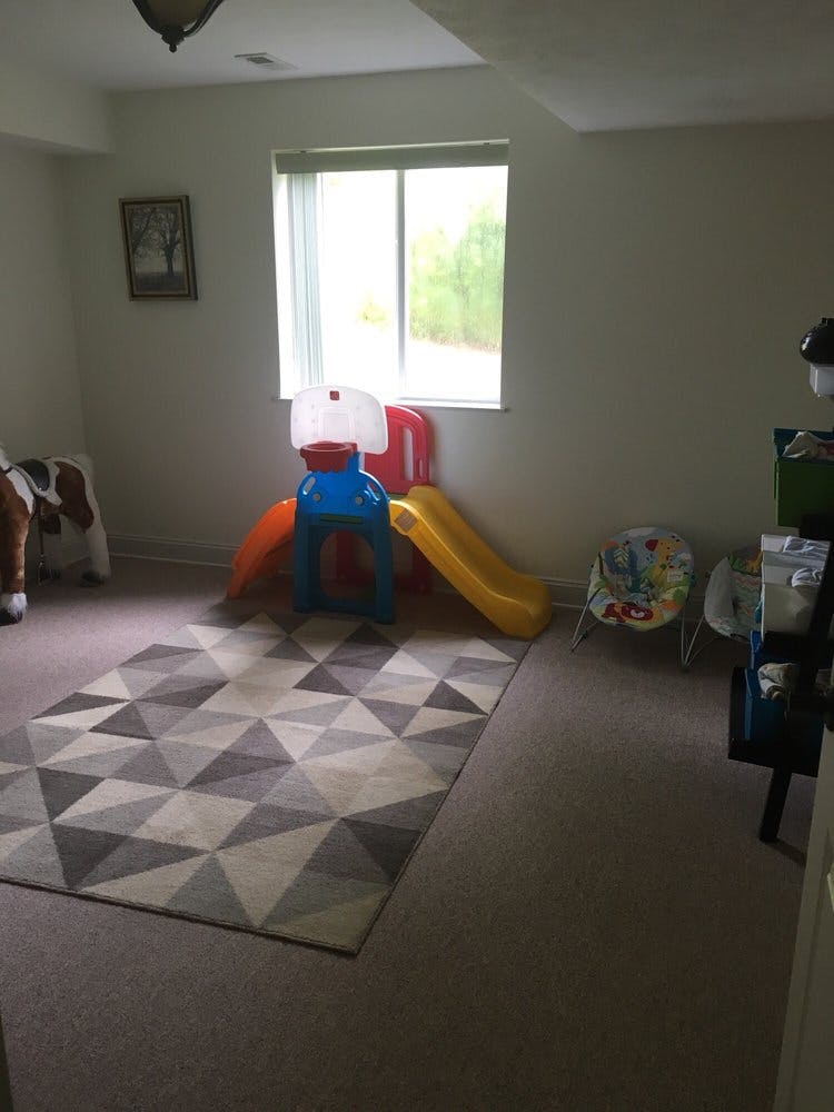 Indoor play area with a small slide, basketball hoop, and geometric rug