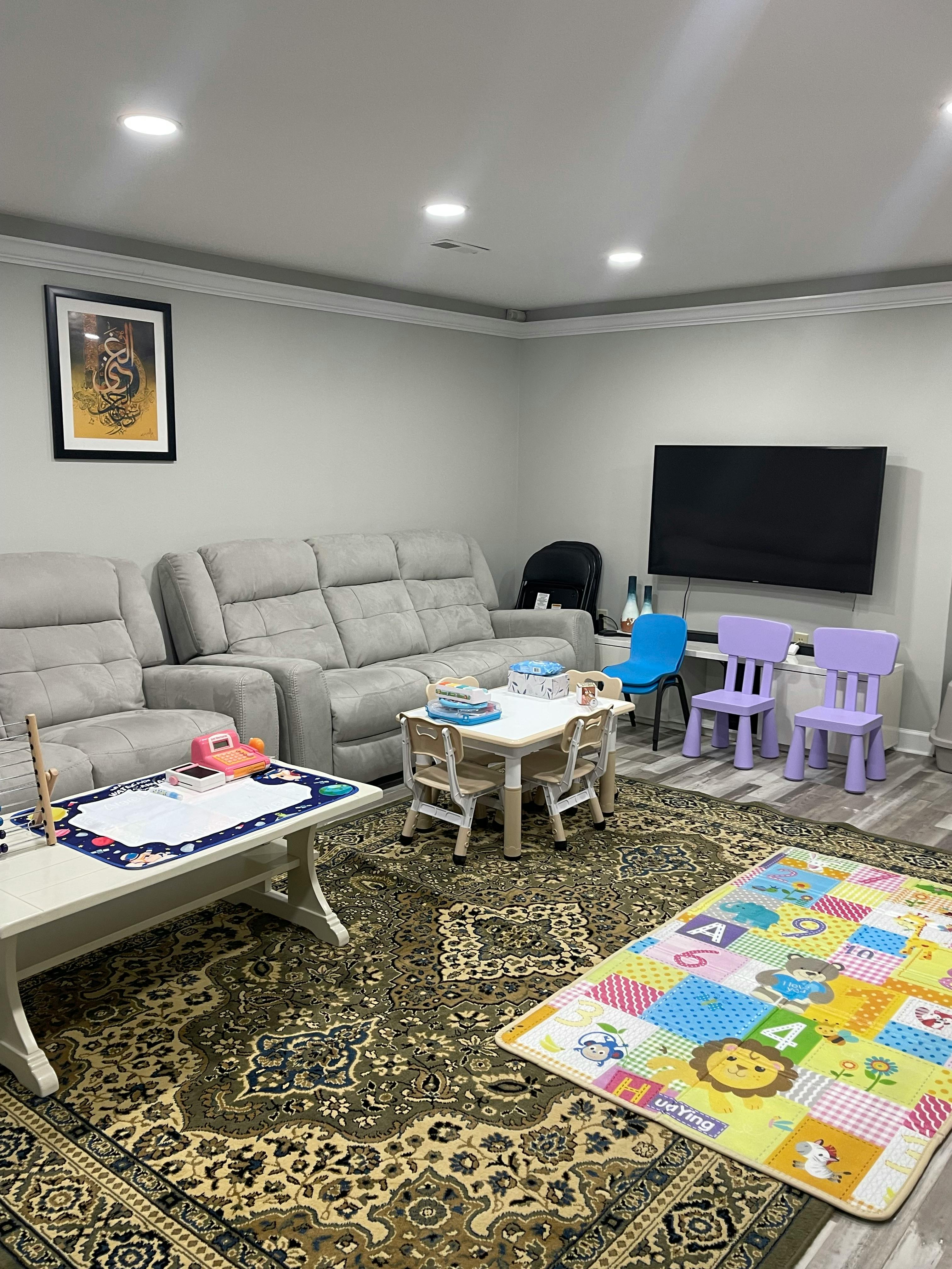 Living room with gray sofas, a TV, and children's tables and chairs