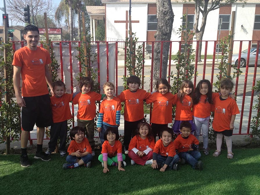 Adult and group of children in orange shirts posing outdoors