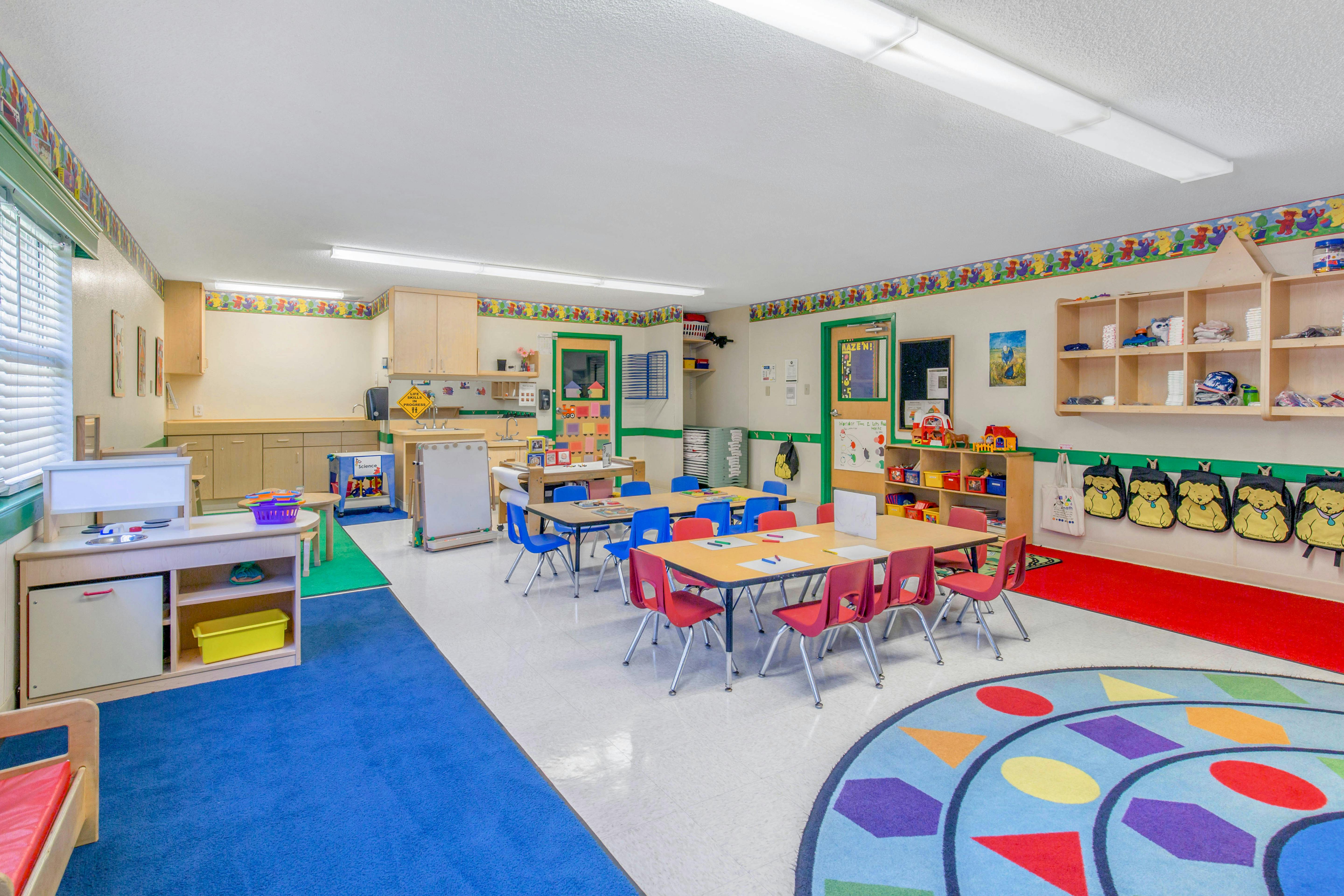 Colorful and organized classroom with tables, chairs, and play areas