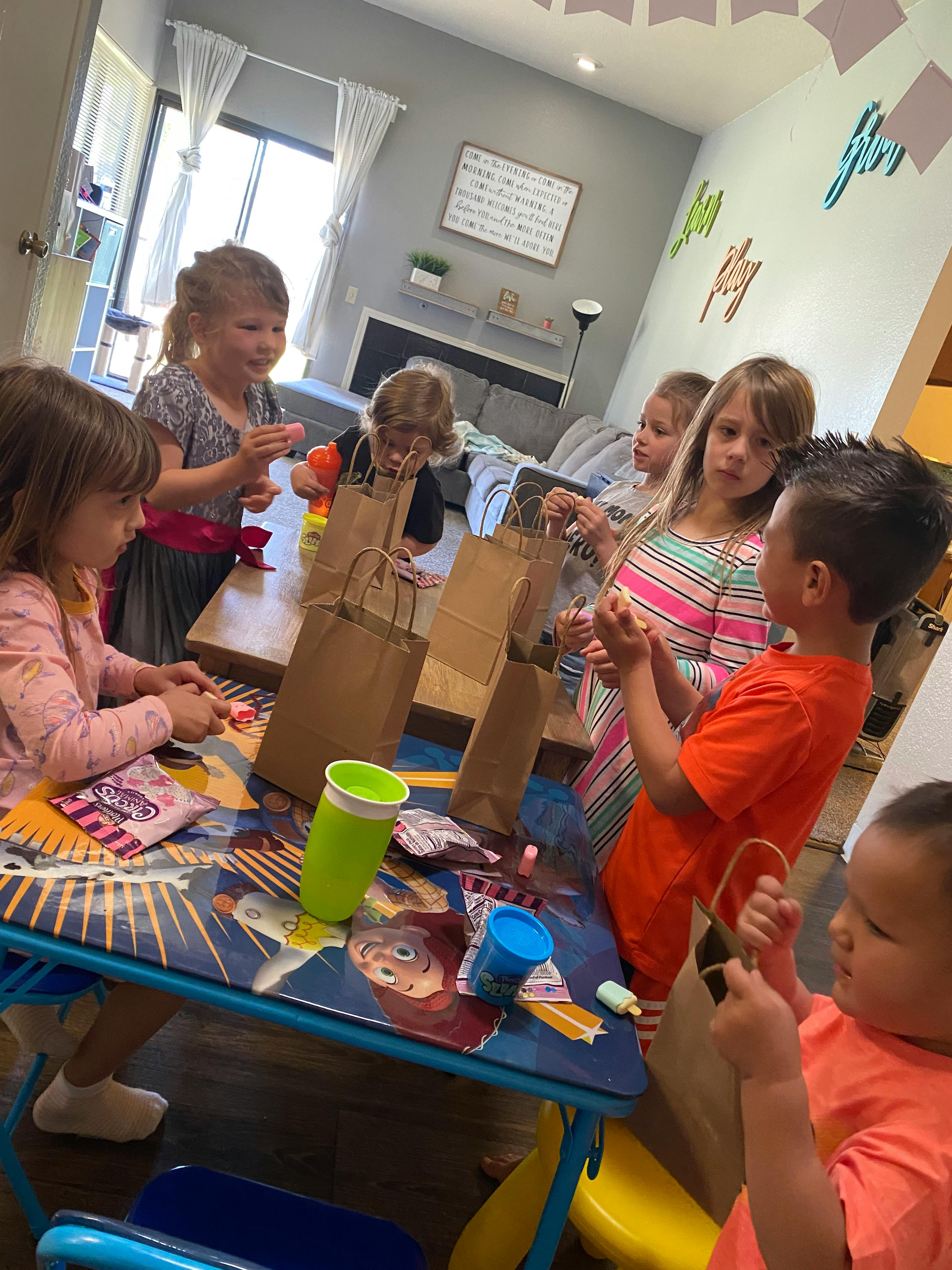 Children gathered around a table with craft bags