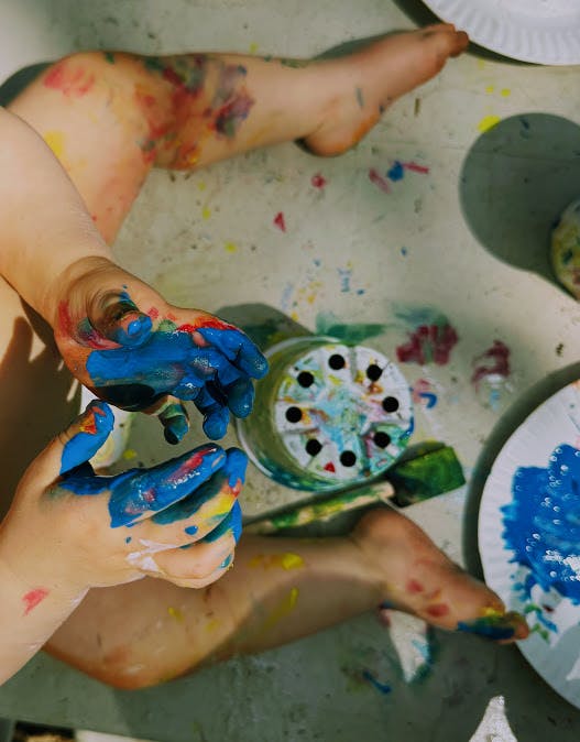 Child's hands and legs covered in paint