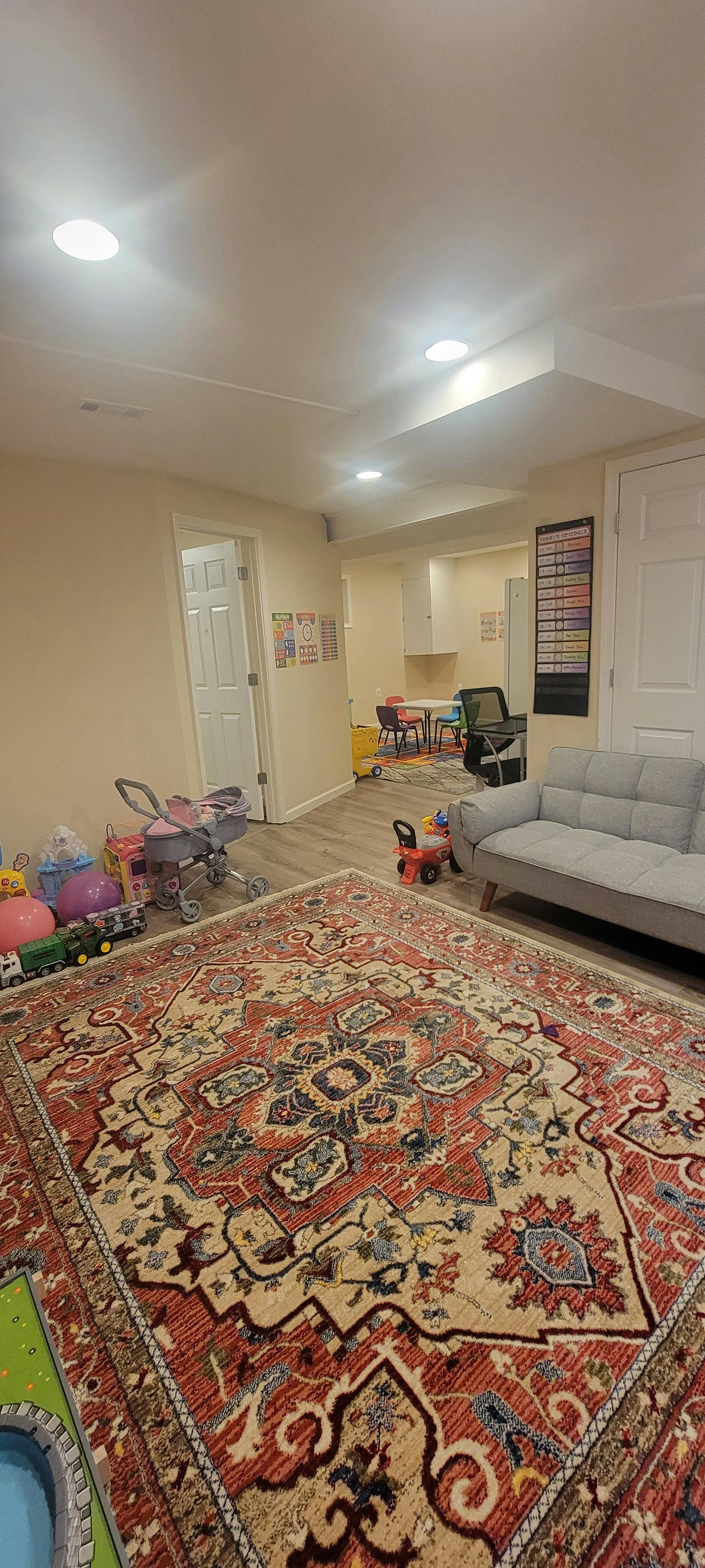 A playroom with an ornate patterned rug, children's toys, and a small sofa