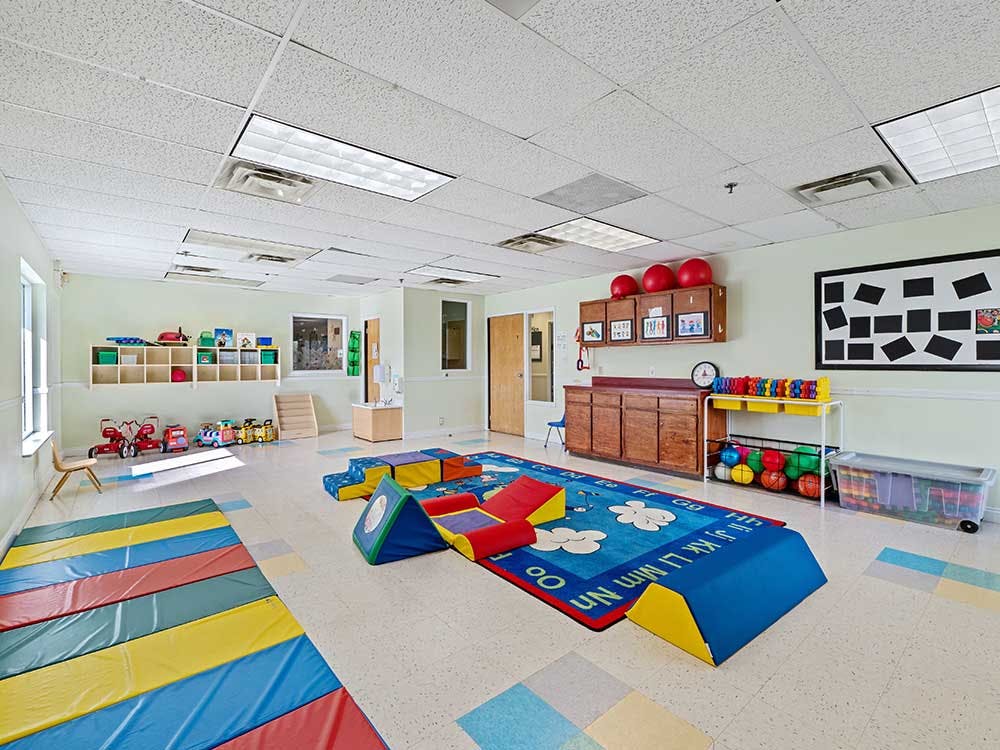 Colorful playroom with soft mats and blocks, a rug, and shelves of organized toys
