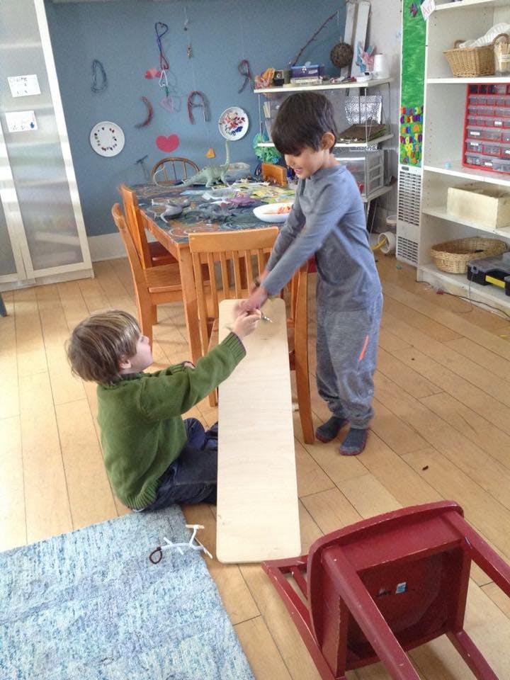 Two children playing with a wooden board in a room