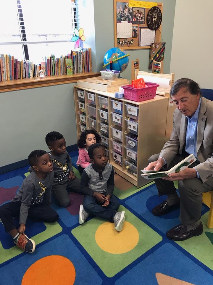 Adult reading a book to children in a classroom