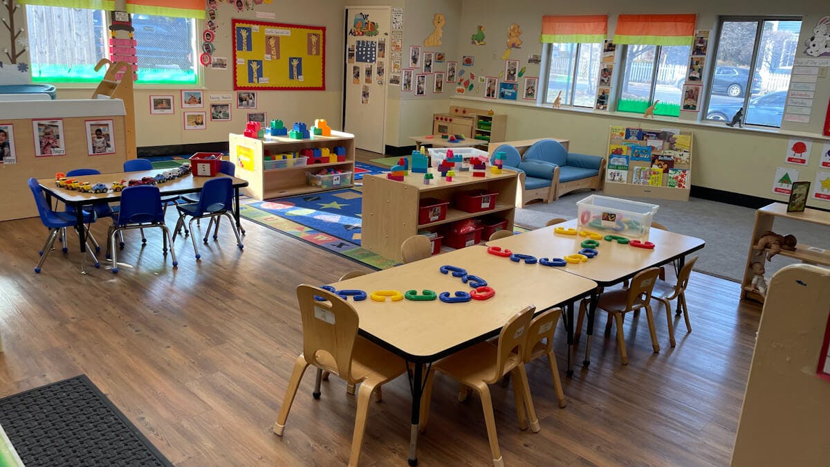 Classroom with child-sized tables and chairs, toys on shelves and tables