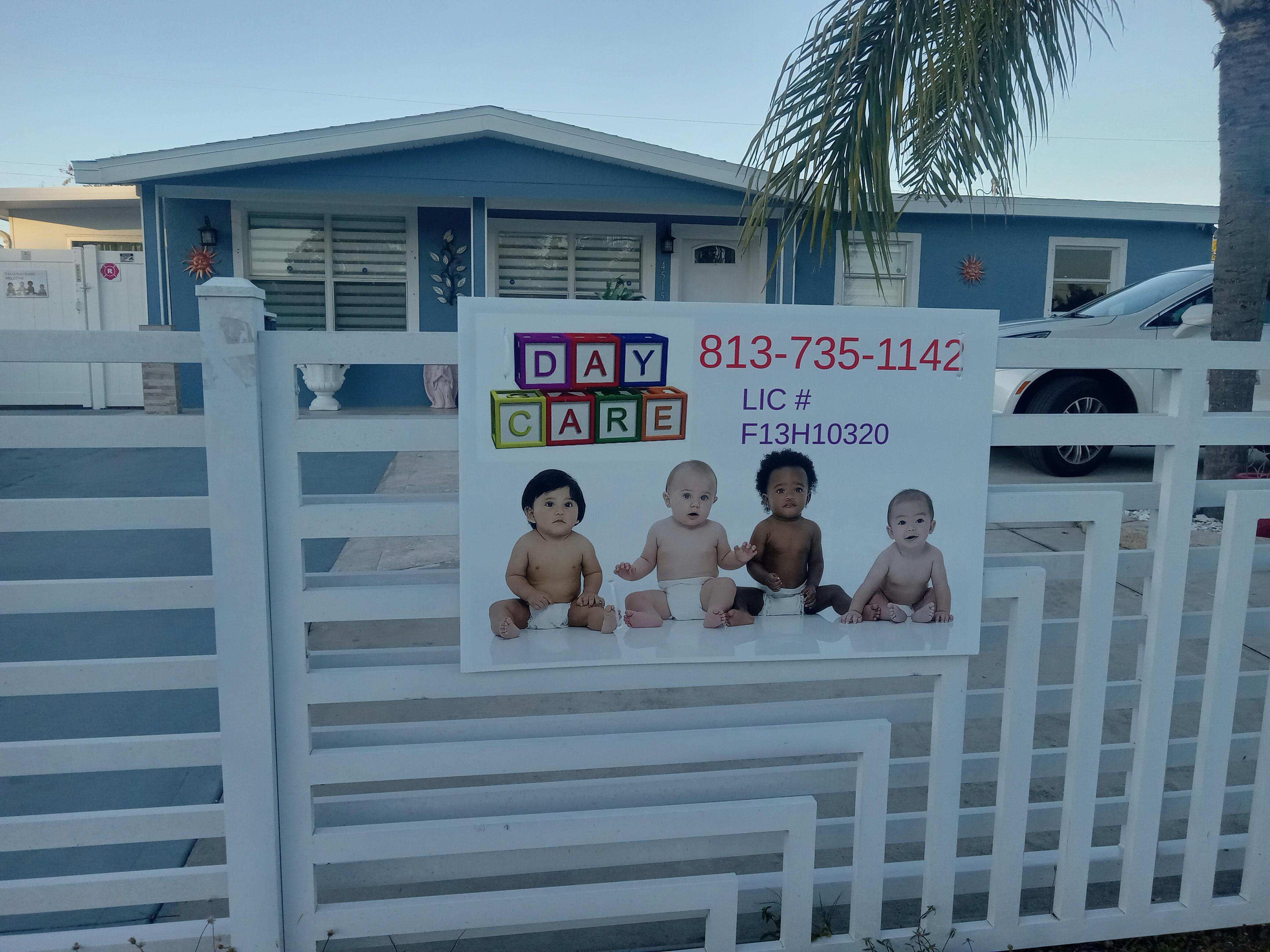 Daycare sign on a white fence with four babies and contact information