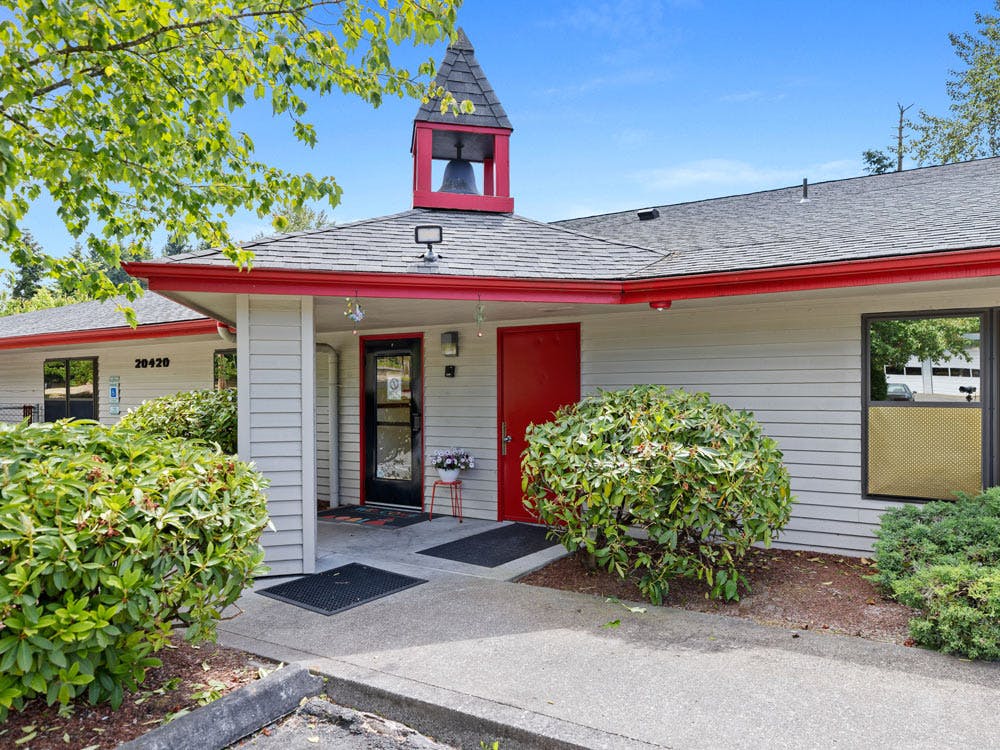 Building exterior with a bell tower and red trim over the entrance
