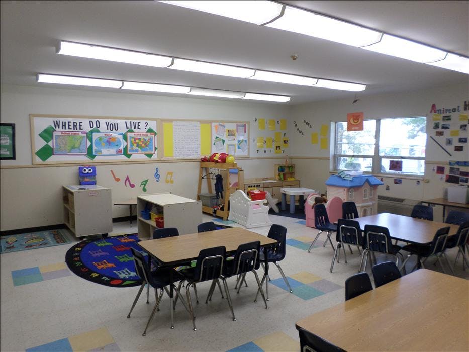 Classroom with tables and chairs, a bulletin board with maps and "WHERE DO YOU LIVE?"