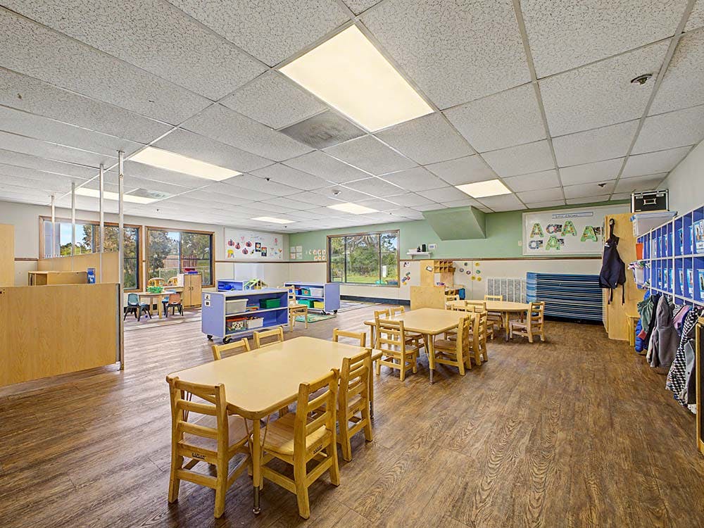 Empty classroom with small tables, chairs, and cubbies