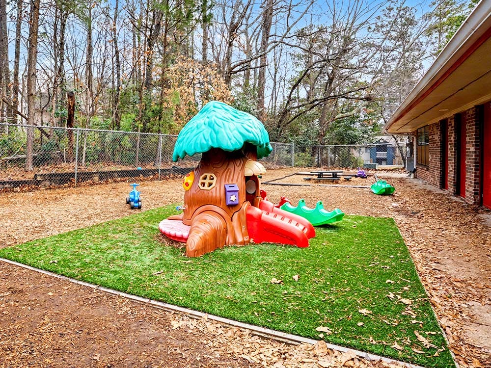 Playground with a treehouse slide and fake grass