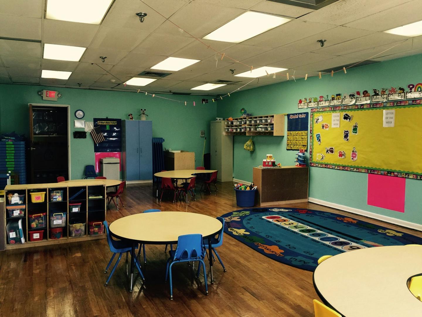 Classroom with small tables and chairs, a rug, and bulletin boards