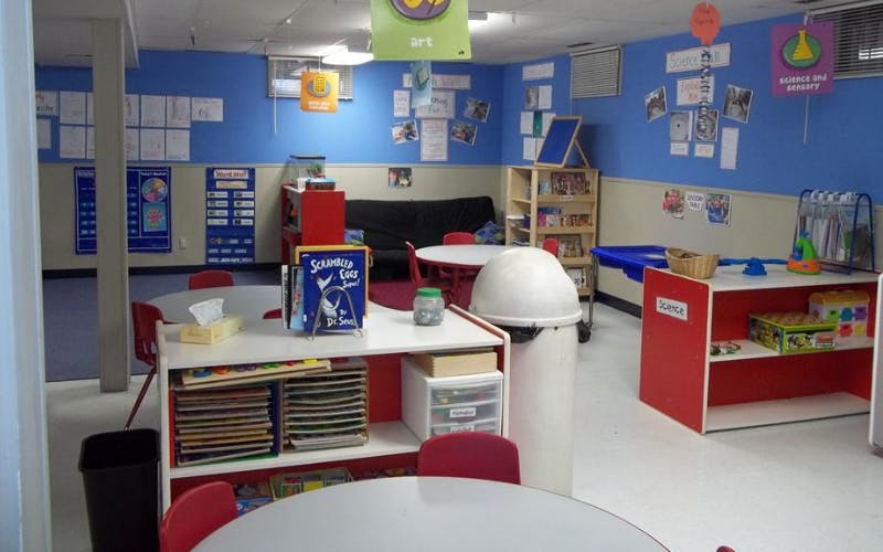 Classroom with tables, chairs, shelving units, and educational posters on the walls