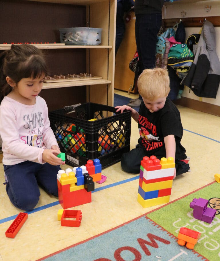 Two children playing with colorful building blocks on the floor