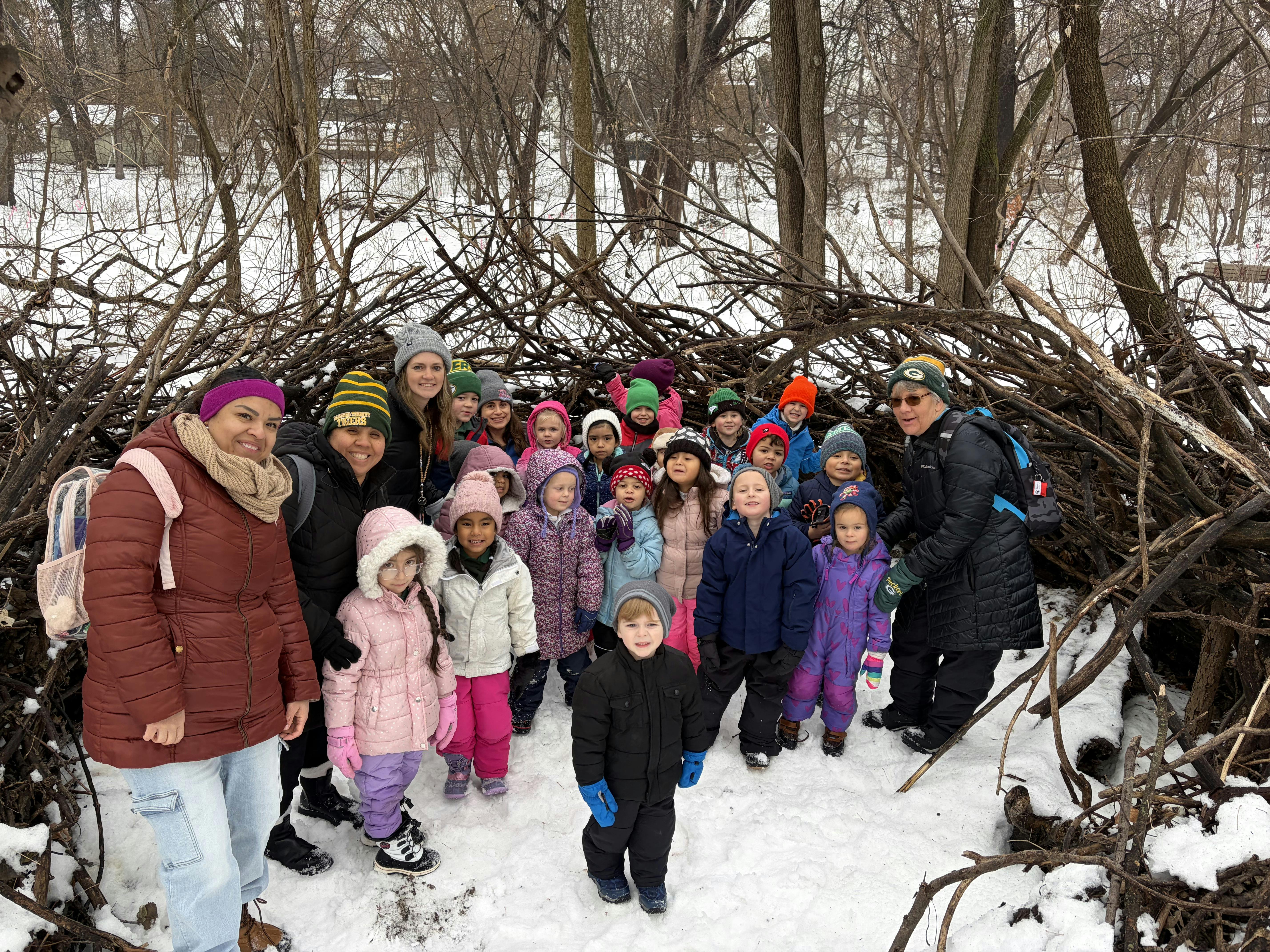 Group of adults and children in winter clothes in a snow-covered forest